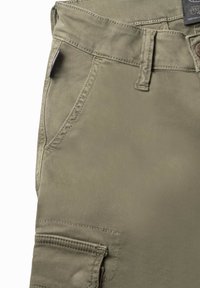 Olijfgroene cargobroek met een gladde textuur, voorzakken en een patchzakdetail aan de zijkant. Knopsluiting en gestikte naden.
