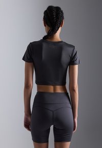 Black activewear set featuring a cropped t-shirt and high-waisted shorts. Smooth texture, minimal branding, and fitted design.