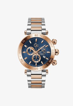 Guld- og sølvfarvet rustfri ståluhr med en blå tekstureret urskive, tre under-dialer og en tachymeter-bezel. Quartz bevægelse, datovisning.