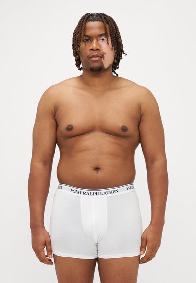 Hvide bomulds boxer briefs med en sort "POLO RALPH LAUREN" elastik i taljen, der har en tætsiddende pasform og glat tekstur. Modellen står oprejst.