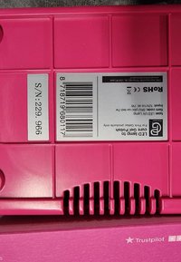 Helderroze plastic LED-lamp met een gestructureerd oppervlak, voorzien van ventilatiesleuven, een streepjescode en een label met productinformatie aan de achterkant.