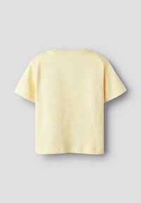 Camiseta amarilla de manga corta con un acabado suave y texturizado. Cuello redondeado y dobladillo limpio, con un patrón salpicado sutil.