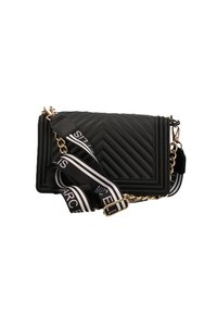 Borsa a tracolla nera trapuntata con un motivo a chevron, hardware dorato e una tracolla a righe nero e bianco con testo e un accento in catena.