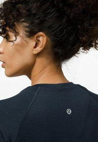 Marinefarbendes Sport-T-Shirt mit kurzen Ärmeln, strukturiertem Stoff und einem reflektierenden Logo auf dem Rücken. Verfügt über eine normale Passform mit Nahtdetails.