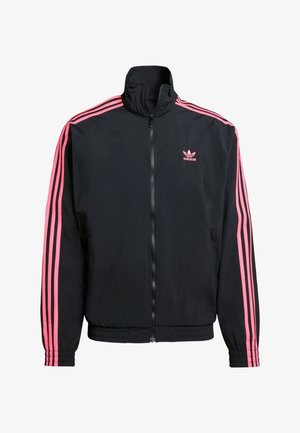 Veste noire zippée avec col haut, accents roses à trois rayures sur les manches et un petit logo rose sur la poitrine gauche. Texture lisse.