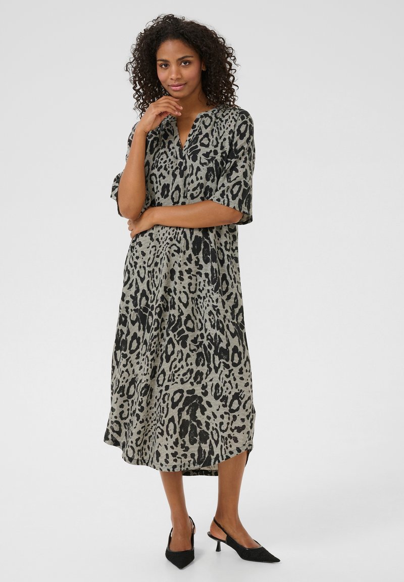 Robe mi-longue à manches courtes, en imprimé léopard beige avec des taches noires. Elle présente un décolleté en V et une silhouette ample et fluide.