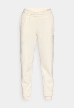 Pantaloni jogger color crema realizzati in morbido tessuto, dotati di una vita elastica, design a gamba affusolata e una piccola patch con logo sul lato.