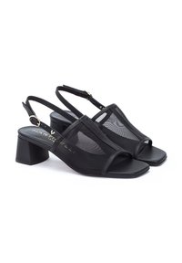 Tacones slingback negros con diseño de malla, punta cuadrada y tacón cuadrado. Acentuados con un logo metálico dorado en la plantilla.