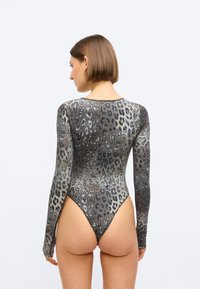 Bodysuit de manga longa em tecido transparente, com estampa de leopardo em tons de cinza e preto, com perna alta e design de costas cavadas.