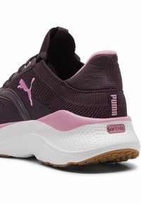 Violetiniai megzti sportbačiai su rožiniais akcentais, tekstūruota kulkšnies dalis ir balta minkšta padas. Yra matoma Puma logotipas ir Softride technologija.