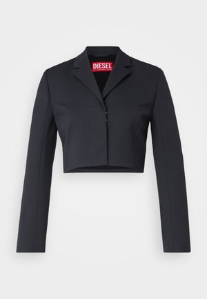 Przycięty czarny żakiet z gładkiego materiału, z kołnierzem łezkowym, zapięciem na jeden guzik i długimi rękawami. Wewnątrz widoczna czerwona metka marki.