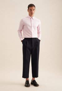 Camicia button-up rosa chiaro, pantaloni plissettati blu navy scuro e scarpe in pelle nere. Design semplice con colletto classico e vestibilità su misura.