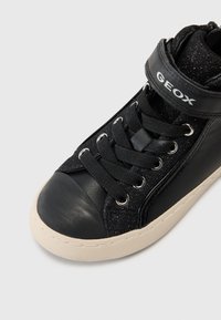 Svart høytopp sneaker med overdel i lær og glitrende tekstil, gummitåhette og snøring. Har en stropp med "GEOX"-logo.