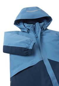 Svetlomodrá bunda s tmavomodrou spodnou časťou, obsahujúca kapucňu, elastické manžety, zips a reflexné detaily na kapucni.