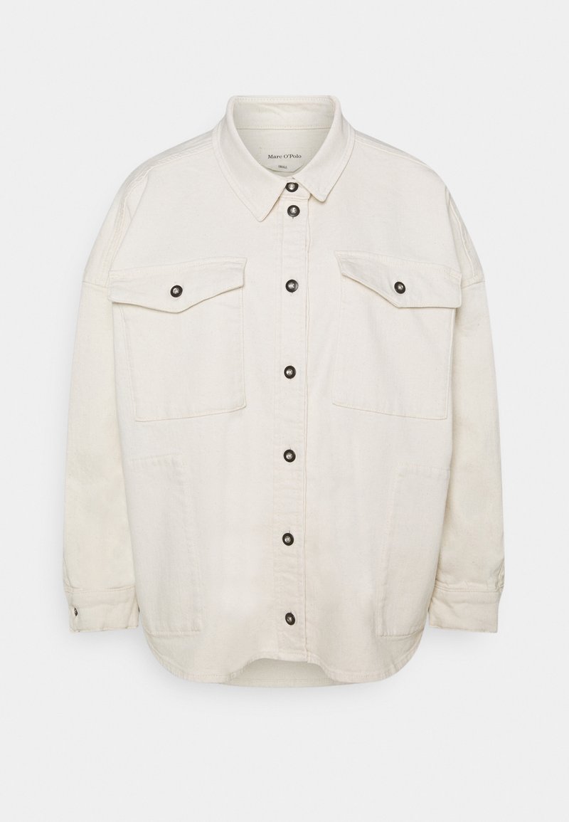 Beżowa, oversize'owa koszula-kurtka wykonana z bawełny, z przodem zapinanym na guziki, dwoma kieszeniami na piersi i czarnymi zatrzaskami. Posiada długie rękawy i zaokrąglony dół.