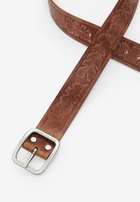 Ceinture en cuir marron avec un motif de feuilles en relief, boucle en métal argenté et plusieurs trous pour l'ajustement. Texture lisse et forme rectangulaire.