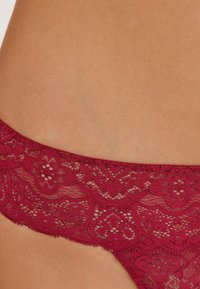 Sous-vêtements en dentelle bordeaux avec des motifs floraux, des détails complexes et un bord festonné. Tissu lisse contre la peau.