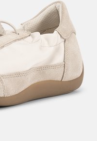 Μπεζ και άσπρο casual παπούτσι με τακούνι από σουέντ, επάνω μέρος από ύφασμα, επενδυμένο γιακά και ελαφριά καφέ λαστιχένια σόλα, εμφανιζόμενο από το πλάι.