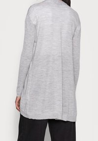 Ljusgrå, långärmad cardigan gjord av ett mjukt, strukturerat stickat material. Har en avslappnad passform, med sidoklyftor och en ribbad halsringning.