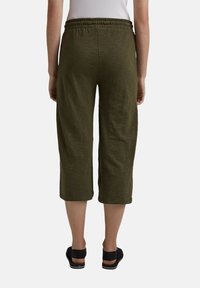 Pantaloni cropped verde oliva con cintura elastica, realizzati in un tessuto morbido e testurizzato. Nessuna tasca visibile o motivi distintivi.