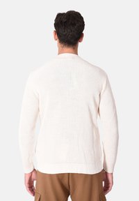 Maglione beige chiaro a maglia con trama a costine, maniche lunghe e scollo rotondo, con orlo dritto e senza dettagli visibili.