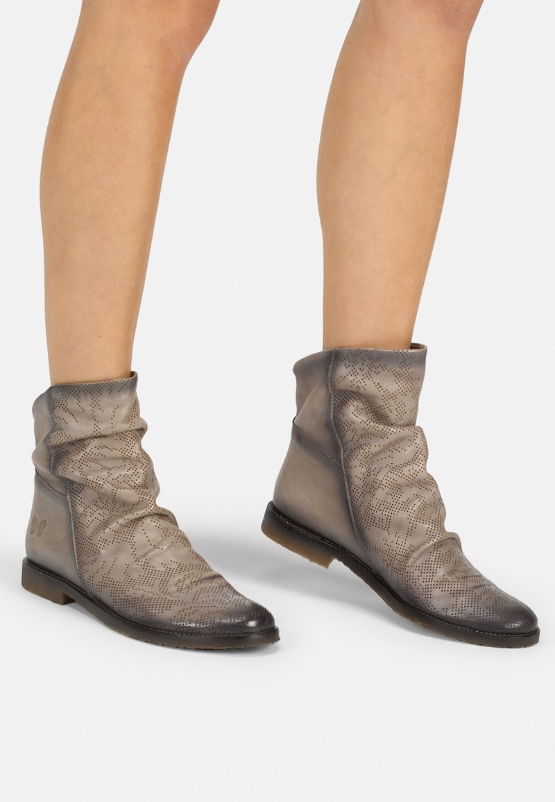 Botas de tobillo de cuero gris con diseño arrugado, patrones perforados, punta redonda y tacón bajo. Textura suave con acabado mate.