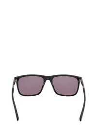 Suorat aurinkolasit, joissa on mustasta muovista valmistettu runko ja violettisävyiset linssit. Varret ovat ohuita mustia ja saranan lähellä on hopeisia metallikoristeita.