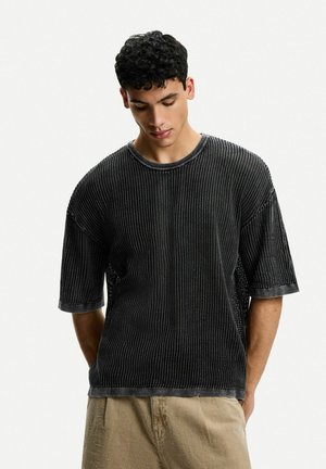 Schwarz kurzärmliges T-Shirt mit vertikal gerippter Textur, rundem Halsausschnitt und weichem Stoff. Verfügt über eine lockere Passform und einen subtilen Glanz.