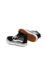 Zapatillas negras y grises que combinan materiales de gamuza y malla, cordones blancos, una entresuela blanca gruesa y una suela de goma texturizada marrón.