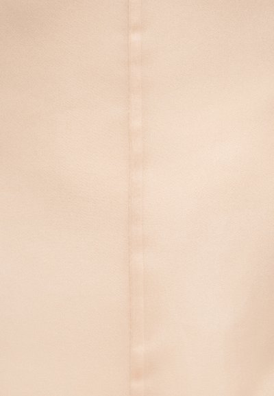 Λεπτομέρεια ραφής σε λείο, μπεζ ύφασμα που δείχνει διακριτή υφή και κάθετη γραμμή ραφής στο κέντρο.