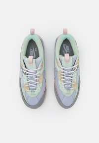 Sneaker Nike con un design a materiali misti in verde menta, grigio e accenti pastello. Texture uniche e dettagli di cucitura intricati visibili.