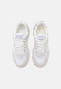 White sneakers with mesh and suede accents, featuring a round toe, lace-up front, and a cushioned sole. Branding on the tongue.