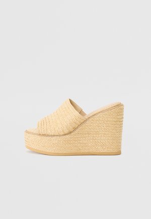 Sandalette compensée en paille naturelle, présentant un dos fermé et un design à bout ouvert, avec une surface texturée et une semelle plateforme.
