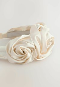 Bandeau en satin couleur blanc cassé avec deux accents de roses superposées, présentant une texture lisse et des pétales courbés, fixé à un bandeau recouvert de tissu.