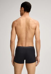 Mustat bokserishortsit, joissa on kuvioitu harmaa vyötärönauha, istuva malli ja sileä kangaspinta, nähtynä mallin selän puolelta.