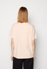 Short-sleeve T-shirt in light pink cotton, featuring a relaxed fit and a crew neck. Smooth texture with no visible patterns or accents.