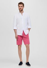 Witte linnen shirt met lange mouwen, roze shorts en marineblauwe instappers. Gladde textuur, met knoopjes en een casual pasvorm.