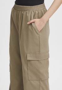 Kaki cargobyxor har en elastisk midja och sidoficka. Det mjuka, lätta tyget har en avslappnad passform och är draperat vid midjan.