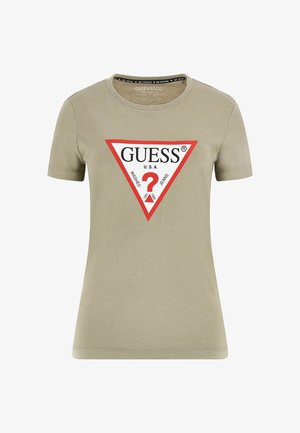 Īsām piedurkņu olīvu zaļš T-krekls ar apaļu kakla izgriezumu, ar trīsstūra grafiku sarkanā un baltā krāsā, uz kuras ir teksts "GUESS U.S.A" un jautājuma zīme.