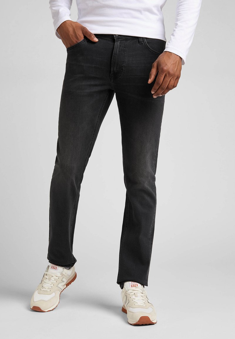 Mörka denimjeans med slim fit, femficksdesign och en lätt blekning. Bärs med ljusa träningsskor.