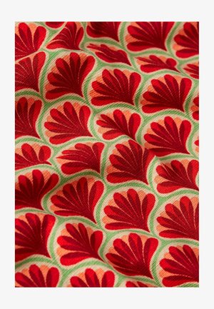 Textil con un patrón repetido de formas de hojas rojas sobre un fondo melocotón claro, rodeado por acentos verdes. Tejido texturizado.