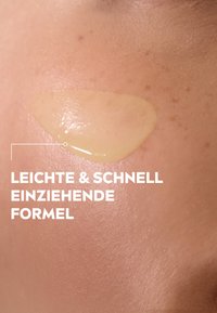 Translucent yellow gel applied to skin, smooth texture, highlighting a natural skin tone with minimal visible imperfections in the background.
