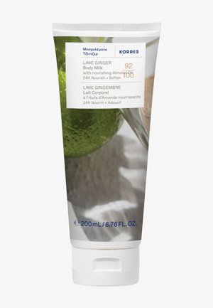 Tube de crème hydratante pour le corps au citron vert et au gingembre de couleur blanche ; présente des images de citron vert vert et de gingembre beige ; étiqueté avec des informations sur le produit en texte bleu.