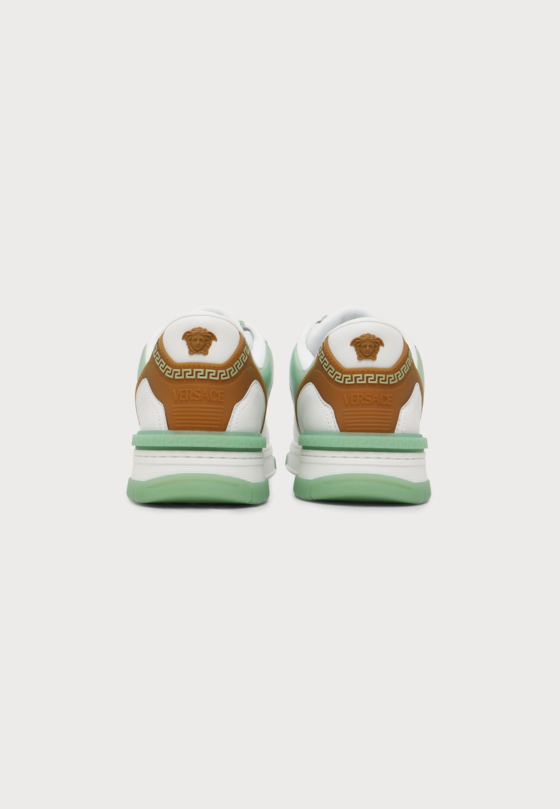 Pair of white sneakers with light green soles and brown heel accents, featuring Versace logo and Medusa head on the back.