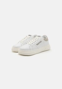 White leather sneakers with a beige heel accent and subtle branding on the side; round toe and textured rubber sole.