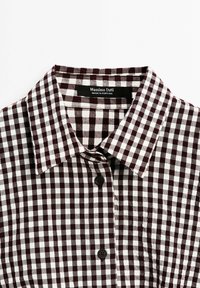 Chemise boutonnée à col avec motif à carreaux marron foncé et blanc et étiquette Massimo Dutti visible à l'intérieur du col.