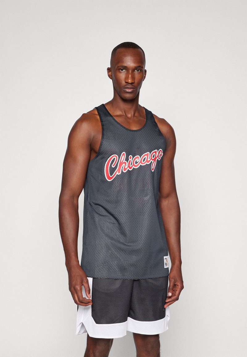 Parte superior de baloncesto de malla negra con letras rojas de "Chicago", con un corte relajado y combinada con pantalones cortos deportivos en blanco y negro.