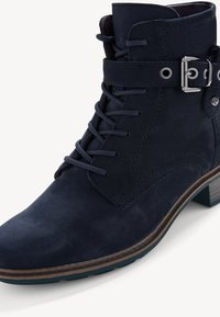 Bottine en cuir bleu marine avec un laçage à l'avant, détail de boucle sur le côté et un talon en bois. Texture lisse et design à bout rond.