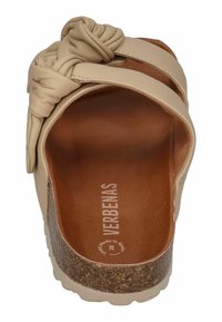 Beige slip-on sandal with a knotted leather accent, cork midsole, and textured footbed. Branding visible on the insole.