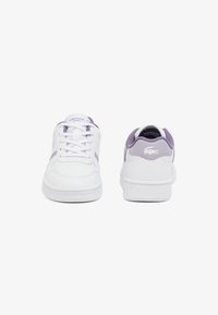Baskets blanches avec des accents lavande, dotées d'un dessus en cuir, d'un bout rond, d'un système de laçage et d'une semelle extérieure en caoutchouc texturé. Logo Lacoste sur le côté.